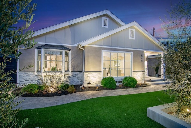 view of front of property with stone siding, board and batten siding, and a front lawn