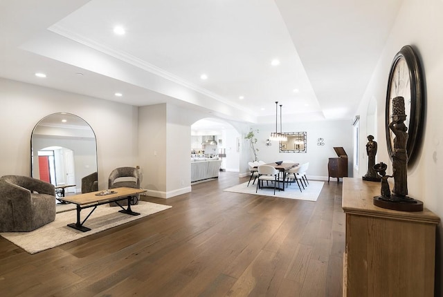 interior space with dark wood-type flooring, baseboards, a tray ceiling, recessed lighting, and arched walkways