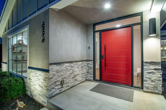 doorway to property with stucco siding and stone siding