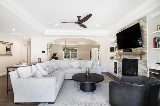 living room featuring arched walkways, crown molding, and wood finished floors