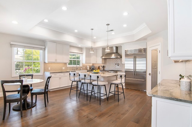 kitchen featuring wall chimney exhaust hood, white cabinets, built in refrigerator, and dark hardwood / wood-style flooring