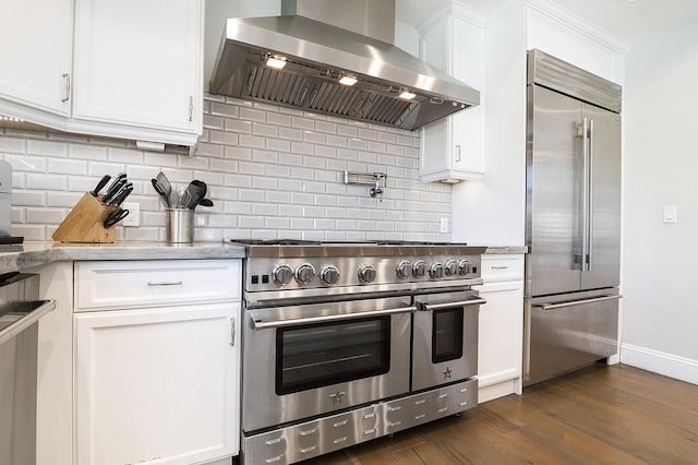 kitchen featuring dark wood finished floors, white cabinetry, wall chimney range hood, high quality appliances, and tasteful backsplash