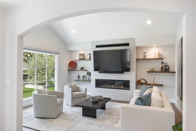 living room with vaulted ceiling and a large fireplace