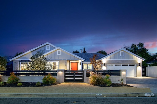 view of front facade featuring driveway, an attached garage, board and batten siding, and a fenced front yard