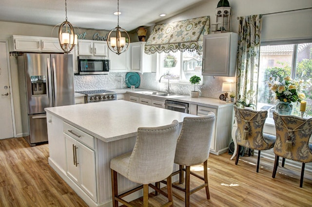 kitchen with appliances with stainless steel finishes, light hardwood / wood-style floors, white cabinetry, a center island, and sink