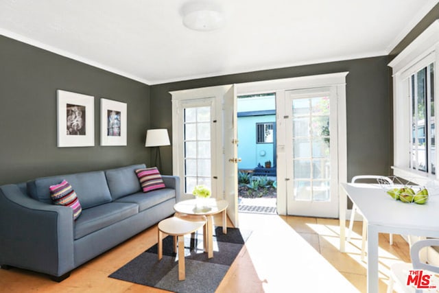 living room featuring wood-type flooring, ornamental molding, and french doors