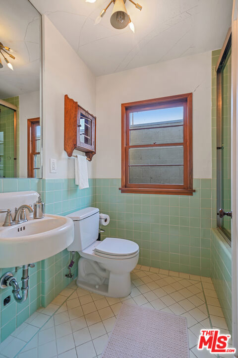 bathroom featuring tile walls, walk in shower, and toilet