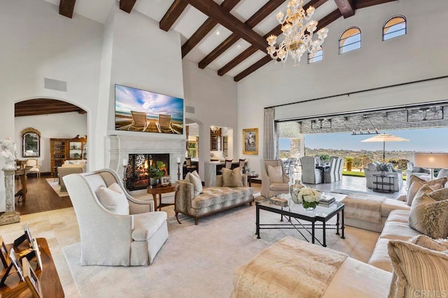 living room with a notable chandelier, light wood-type flooring, beam ceiling, and high vaulted ceiling