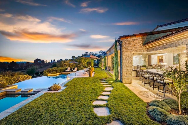 yard at dusk featuring a patio