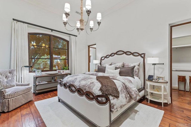 bedroom featuring a notable chandelier, wood-type flooring, and crown molding