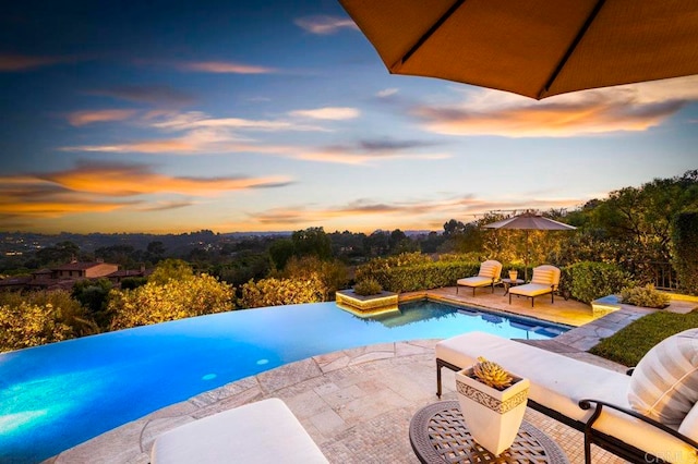 pool at dusk with a patio area