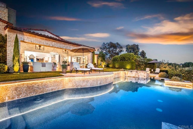 pool at dusk featuring a patio