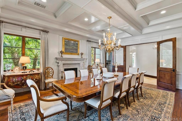 dining room featuring beam ceiling, ornamental molding, wood-type flooring, coffered ceiling, and an inviting chandelier