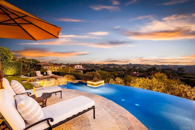 pool at dusk with a patio and an outdoor hangout area