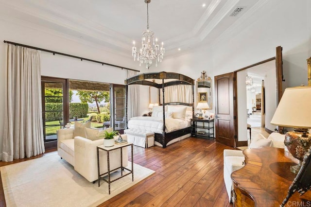 bedroom with a chandelier, a raised ceiling, hardwood / wood-style flooring, and crown molding