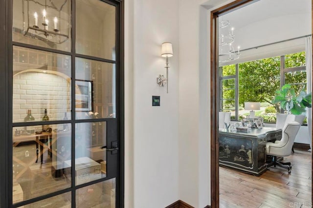 doorway to outside with a notable chandelier and hardwood / wood-style floors