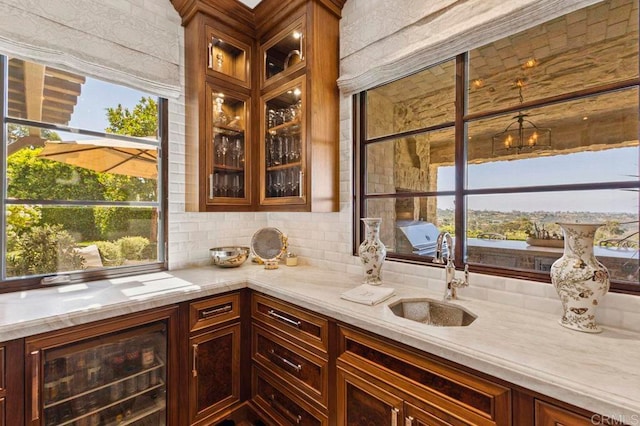 bar featuring light stone countertops, backsplash, sink, and plenty of natural light