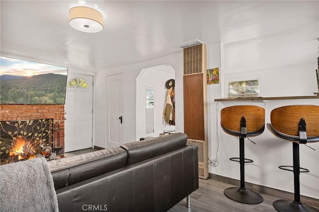 living room featuring a brick fireplace and hardwood / wood-style flooring