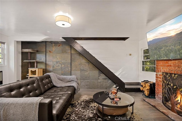 living room featuring a brick fireplace and wood-type flooring