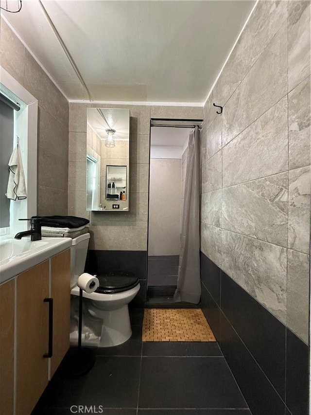 bathroom featuring toilet, tile walls, tile patterned floors, vanity, and curtained shower