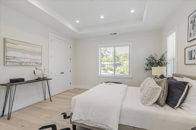 bedroom featuring a tray ceiling and light hardwood / wood-style floors