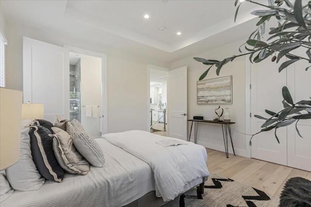 bedroom with light hardwood / wood-style flooring and a raised ceiling