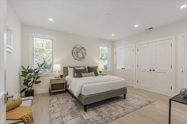 bedroom with two closets and light wood-type flooring