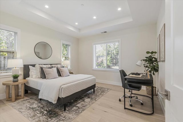 bedroom with a raised ceiling and light hardwood / wood-style flooring