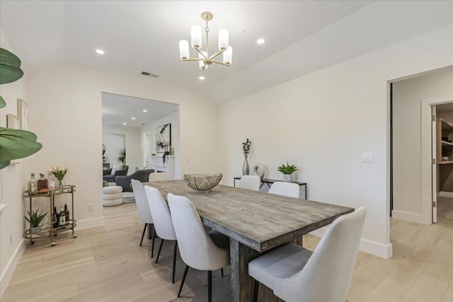 dining space featuring lofted ceiling, light wood-type flooring, and a chandelier