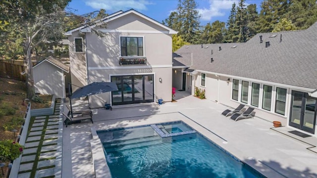 rear view of house with a swimming pool with hot tub and a patio