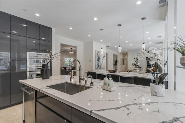 kitchen with appliances with stainless steel finishes, a notable chandelier, hanging light fixtures, light stone countertops, and sink