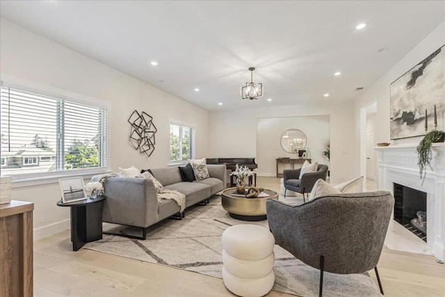 living room featuring light wood-type flooring, a high end fireplace, and an inviting chandelier