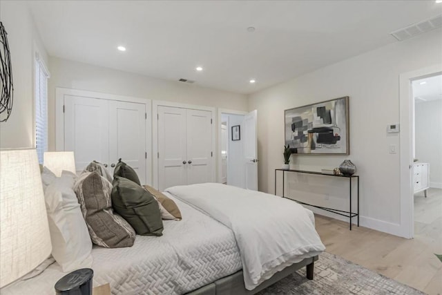 bedroom featuring light hardwood / wood-style floors and two closets