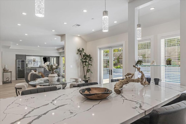 kitchen with light stone countertops, pendant lighting, french doors, and a healthy amount of sunlight