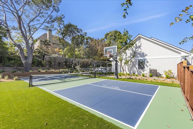 view of sport court featuring tennis court and a lawn