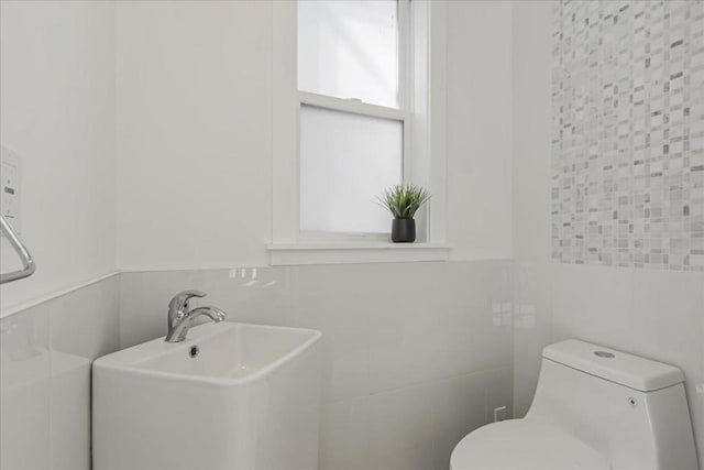 bathroom with toilet, sink, tile walls, and decorative backsplash