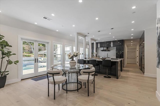 dining space with french doors, plenty of natural light, and light hardwood / wood-style flooring