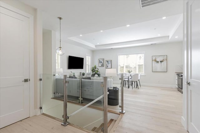 living room with light hardwood / wood-style flooring and a tray ceiling