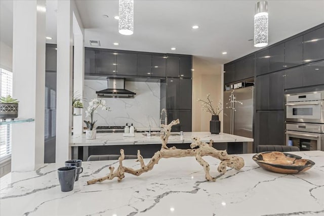 kitchen featuring appliances with stainless steel finishes, decorative light fixtures, light stone countertops, range hood, and sink