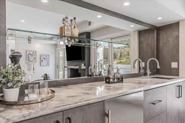 bar with refrigerator, light stone counters, and sink