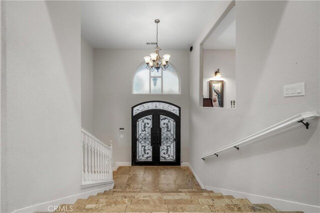 foyer entrance with french doors, baseboards, an inviting chandelier, and stairway