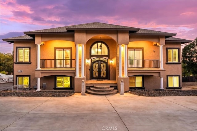 mediterranean / spanish home with covered porch, a balcony, and stucco siding