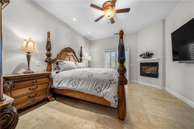 bedroom with a glass covered fireplace, baseboards, recessed lighting, a ceiling fan, and light tile patterned floors