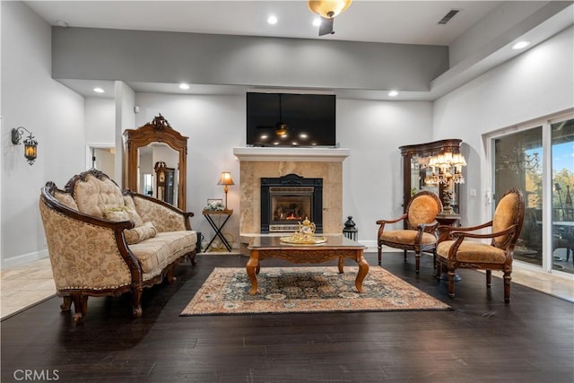 sitting room featuring a towering ceiling, visible vents, recessed lighting, wood finished floors, and a high end fireplace