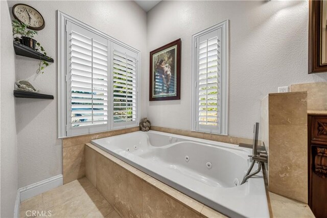 full bathroom with plenty of natural light, a jetted tub, vanity, and tile patterned floors