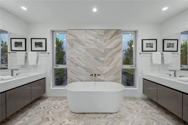 bathroom featuring a wealth of natural light, vanity, and a bathtub