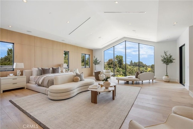 bedroom featuring lofted ceiling, light hardwood / wood-style flooring, and multiple windows