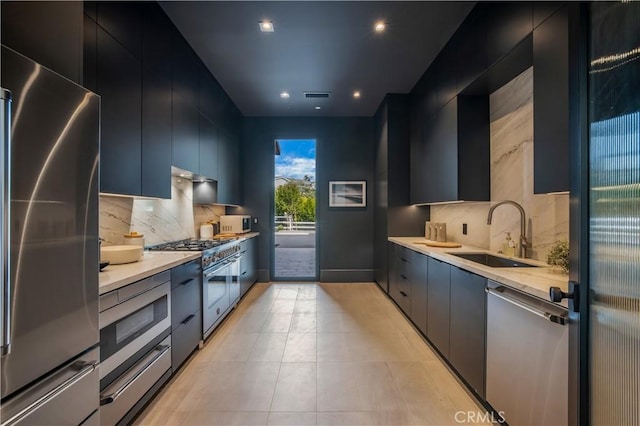 kitchen with backsplash, high end appliances, light tile patterned floors, and sink