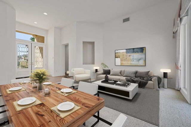 carpeted living room with french doors and a towering ceiling