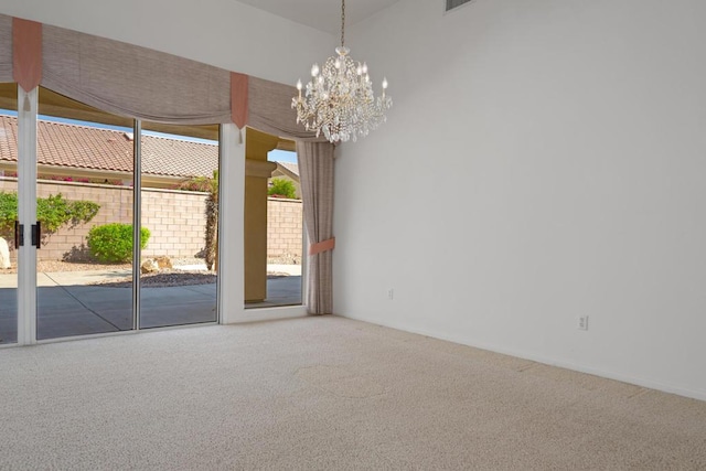 carpeted empty room with a notable chandelier